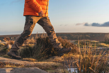 Hiking through scenic landscape at sunset with warm hues reflected on the horizon