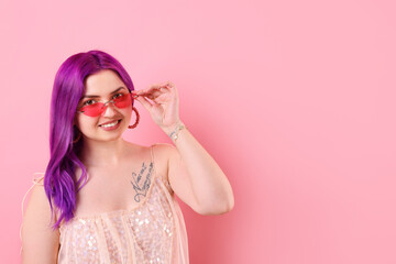 Beautiful woman with bright purple hair and tattoo in Latin on pink background. Space for text