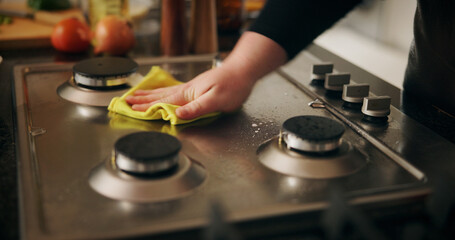 Hand, cleaning stove and man with cloth, hygiene and routine with dirt, home and remove bacteria. Closeup, person and chef in kitchen, wiping and disinfection with responsibility and prevent virus