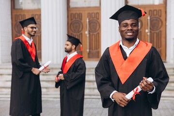 Joyful Group of College Graduates Celebrating Graduation Day in Cap and Gown with Diplomas