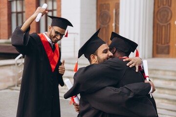 Joyful Graduation Celebration with Friends Hugging and Holding Diplomas Outdoors