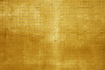 Grungy orange wall made of small square tiles.