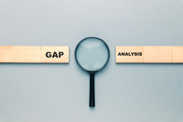 A magnifying glass placed in the gap between the row of wooden pieces, Gap analysis concept