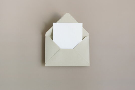 Beige envelope with blank paper card mockup  inside top view on beige background . Copy space.Minimalist aesthetic wedding invitation mockup, greeting card, holiday concept.