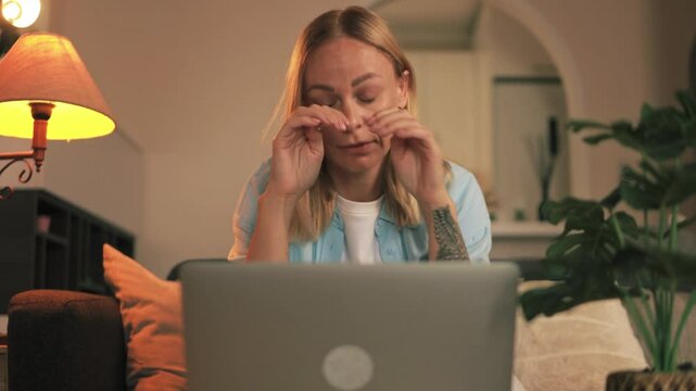 Young woman take off glasse and rub tired eyes in front of laptop, suffering from eye strain, bad vision, dry eye syndrome or computer vision syndrome after long laptop work.Freelance business concept