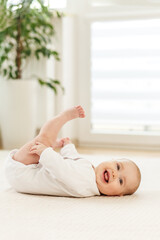 Smiling baby happily playing on the floor during daytime in a bright and cozy room