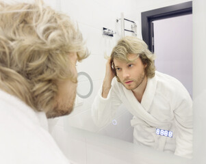 morning routine, young man looking in mirror in bathroom