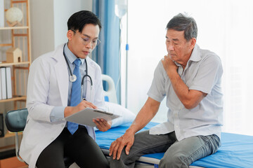 Obraz premium Elderly man pointing to neck and shoulder pain during consultation with a specialist, helping guide diagnosis and care for upper body discomfort.