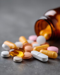 Close-up of assorted pills spilling from a bottle on table, macro medical detail banner