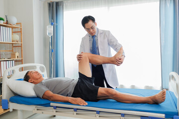 An elderly patient undergoes leg physiotherapy on a treatment bed while being carefully assisted...