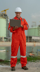 caucasian white engineers in safety uniforms and helmets using laptop and radio for site communication. Concept of teamwork, inspection, and operations at an industrial facility.Construction of Oil, 