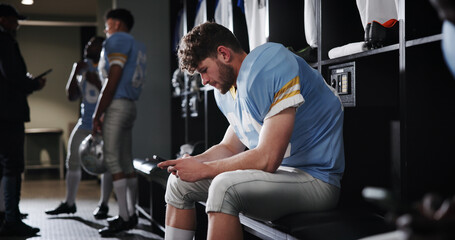 Football, player and athlete with phone in locker room for reading game plan, check notifications and match break. Sports, man and relax with smartphone for social media, online news and mobile chat