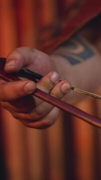 Man in leather clothes plays string instrument with bow at folk music concert on stage closeup. Altai musical instruments. Ancient culture and art