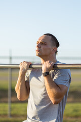Young man performs a chin up at outdoor gym