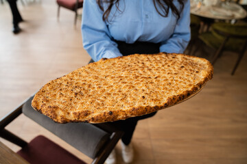Close up view of a waitress holding a big pita bread in her hand.