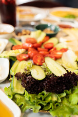 Close up view of vegetables plate with sliced cucumber, tomatoes and lettuce on a breakfast table.