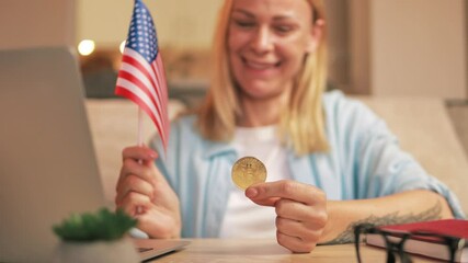 Cheerful female showing bitcoin enthusiasm, waving usa flag near laptop, celebrating digital currency success.Successful trading, cryptocurrency, crypto currency, bitcoin wallet, digital payment.