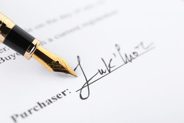 Signature and fountain pen on paperwork, closeup view
