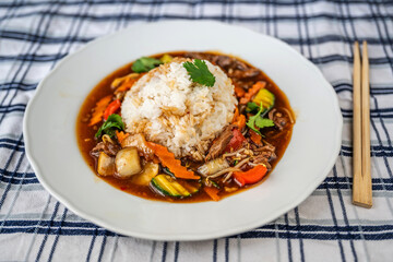 Sichuan spicy meat with sliced vegetable and rice, asian spicy meal in plate with chopstick .
