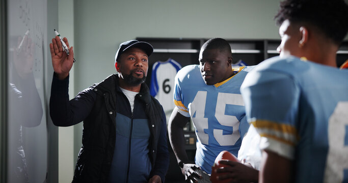 Board, mentor and football with coach and team in locker room for game plan, sports strategy or defense formation. Touchdown tactics, match feedback and discussion with people and training advice