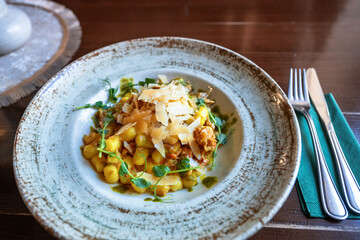 Gnocchi with turkey sauté, pesto and grated parmesan on plate.