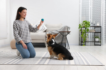 Happy woman with toy training her dog at home