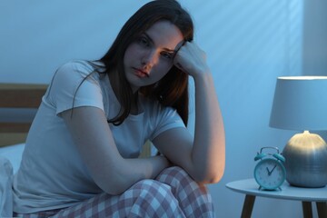 Frustrated young woman suffering from insomnia on bed indoors