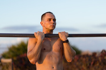 Young man performs a chin up at outdoor gym
