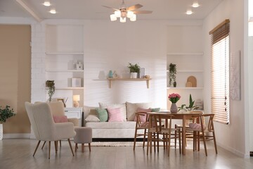 Stylish dining table with chairs and comfortable sofa in room. Interior design
