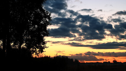 Sunset over village. Evening city landscape. Sunset over multi-story buildings. City line with colorful sky. Cityscape with summer sunset.