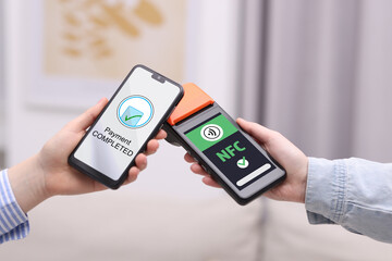 Payment terminal with NFC system. Client using mobile phone to pay for service indoors, closeup