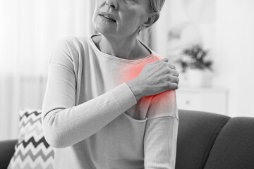 Arthritis. Senior woman suffering from pain in shoulder at home, closeup. Black and white toning...
