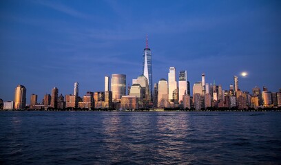 Obraz premium new york city skyline view during blue hour just after sunset (dusk nightfall night time photography from jersey city waterfront) hudson river downtown skyscrapers tall commercial buildings reflecting
