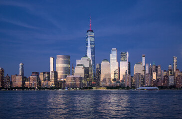 new york city skyline view during blue hour just after sunset (dusk nightfall night time photography from jersey city waterfront) hudson river downtown skyscrapers tall commercial buildings reflecting