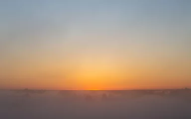 Foto auf Acrylglas Morgen mit Nebel The rising sun on the horizon, thick fog colored by sunlight  © anderus