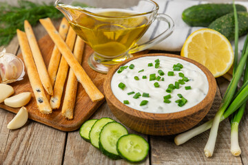 Cucumber sour cream tzatziki sauce on a wooden table.Tartar sauce. Traditional delicious appetizer. yogurt sauce. Tzatziki with ingredients cucumber, garlic,dill,lemon,mint. salad dressing.Copy space