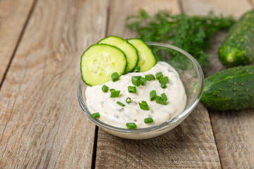 Cucumber sour cream tzatziki sauce on a wooden table.Tartar sauce. Traditional delicious appetizer. yogurt sauce. Tzatziki with ingredients cucumber, garlic,dill,lemon,mint. salad dressing.Copy space