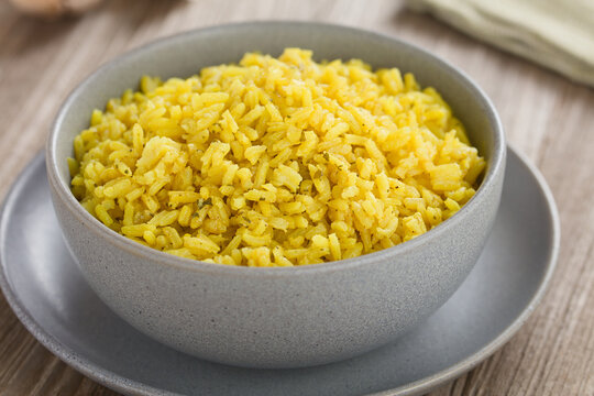 Homemade cooked yellow rice side dish, cooked with turmeric, onion, garlic, salt, pepper and coriander, served in bowl (Selective Focus, Focus in the middle of the image)