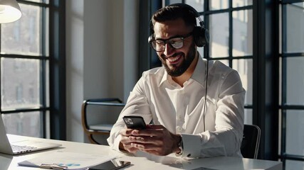 Businessman listening music and browsing smartphone in office