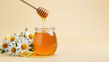 A golden stream of honey pours from a wooden dipper into a glass jar, creating a captivating scene of natural sweetness alongside a bouquet of fresh chamomile flowers and a sliced lemon.  