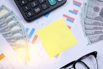 Financial documents and tools arranged with a calculator, money, and a sticky note for notes.