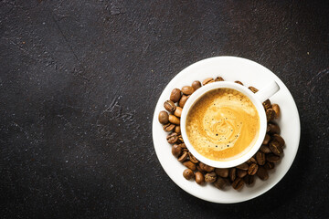 Coffee cup and coffee beans at dark table .