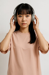 Young Asian Woman in Headphones Listening to Music on Neutral Background