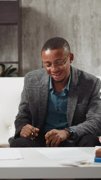 Young African-American man teaches kids to raise hand and listens answers during private English lesson with native speaker at home slow motion