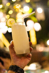 Lemon water, cold blended with a slice of lemon on top and a white straw on hand at night party
