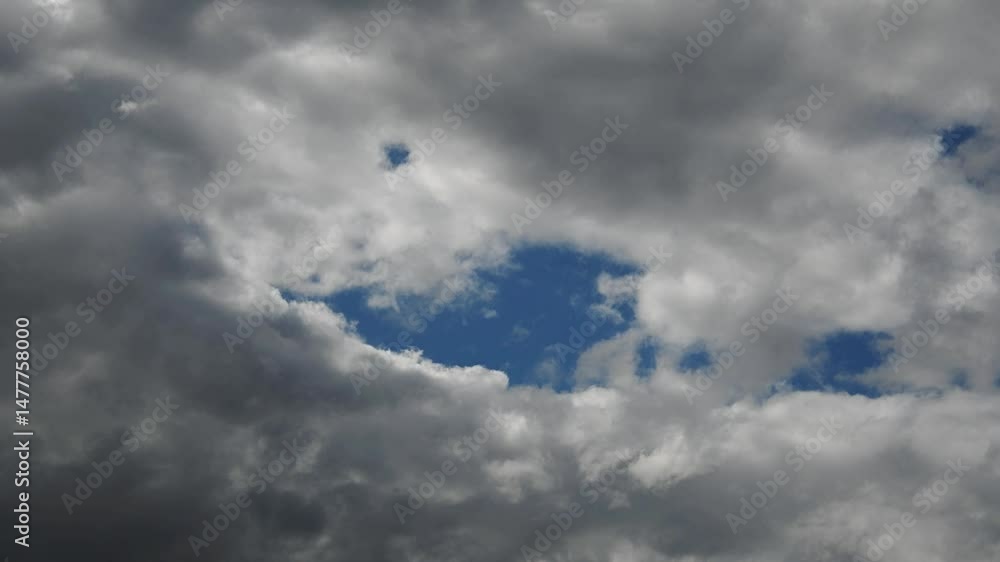Sticker time-lapse of white to gray summer rain clouds moving from left to right with patches of blue