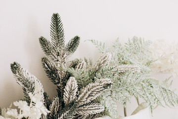 Winter greenery arrangement with frosty leaves and soft white flowers in minimal setting