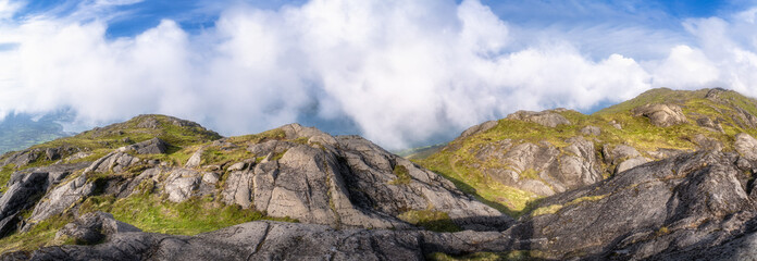 Behold the stunning panoramic view of rugged Slieve Foye mountains beautifully adorned with vibrant greenery, all set under a clear blue sky that is filled with fluffy clouds, Carlingford, Ireland