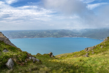 This breathtaking view showcases a serene bay surrounded by lush hills and a cloudy sky, perfect for nature lovers and outdoor enthusiasts seeking adventure, Carlingford, Ireland