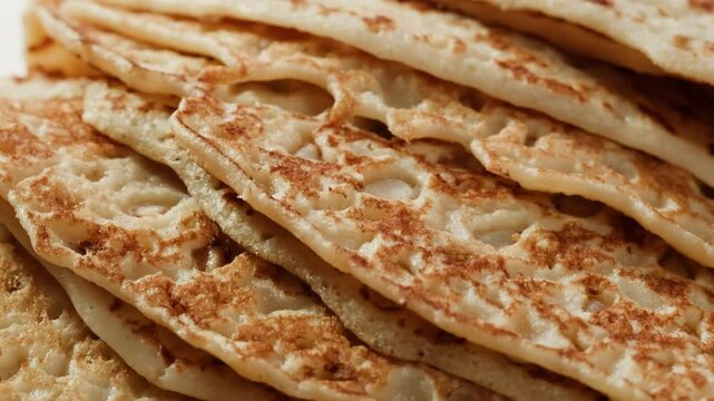 Pancakes with condensed milk on a plate in a restaurant, cutlery, knife and fork cut delicious pancakes poured with condensed milk.